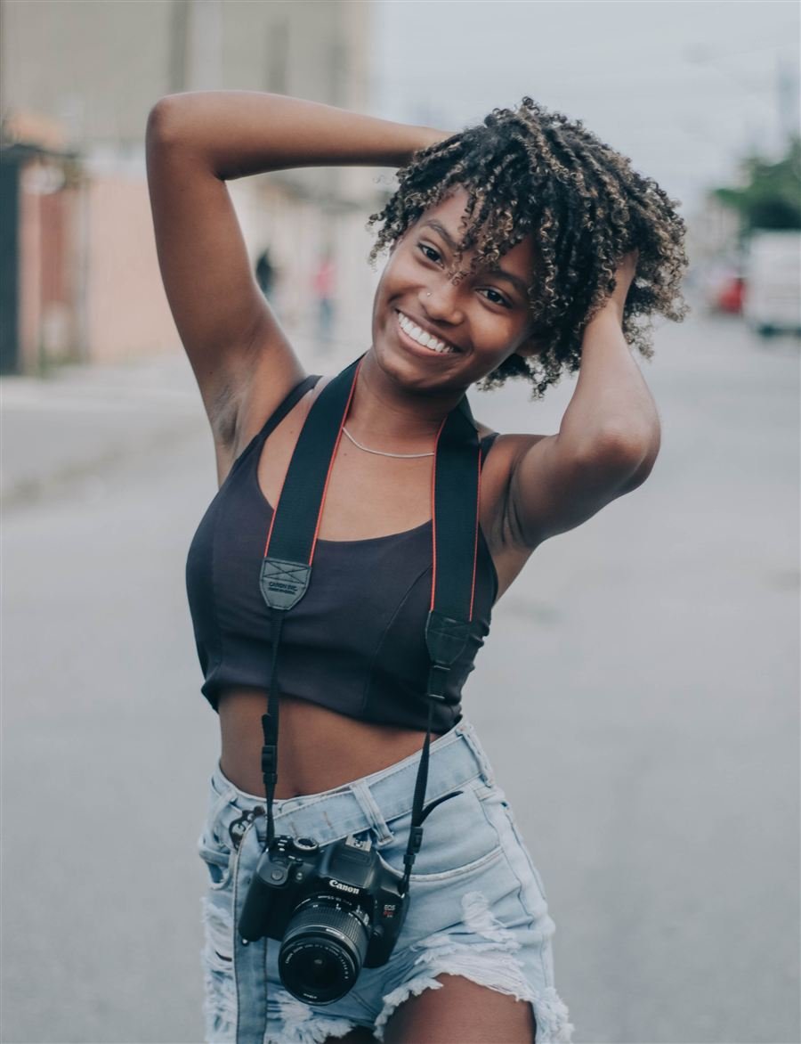 Jovem do Projeto Doulos com câmera fotográfica a tiracolo, representando o protagonismo juvenil em fotografia e vídeo.